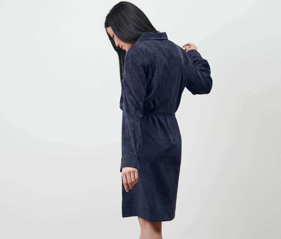 Frau schaut nach unten und trägt ein Cordkleid.