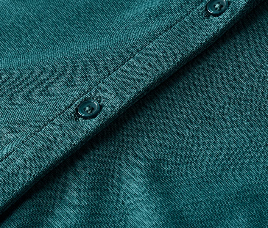 Detailaufnahme eines grünen Strickcardigans mit Knöpfen.
