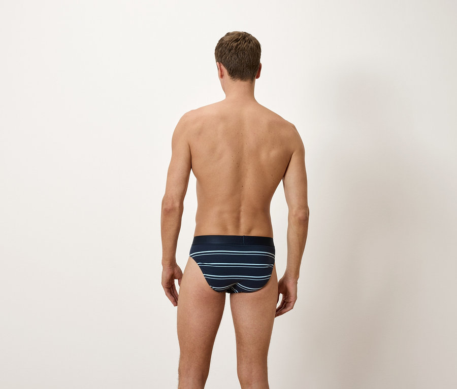 Mann von hinten, trägt blaue Slips mit horizontalen Streifen.