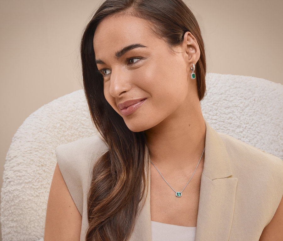 Frau sitzt auf einem Stuhl und trägt eine Halskette und Ohrringe.