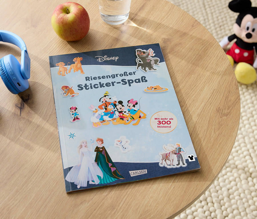 Auf einem Tisch liegen blaue Kopfhörer, ein Apfel, ein Glas Wasser, ein Disney-Stickerbuch und ein Mickey-Mouse-Stofftier.