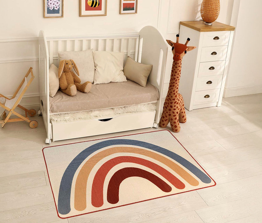 Ein Kinderzimmer mit einem weißen Kinderbett, einer Spielzeuggiraffe und einem »Rainbow« Kinderteppich im Vintage-Stil.