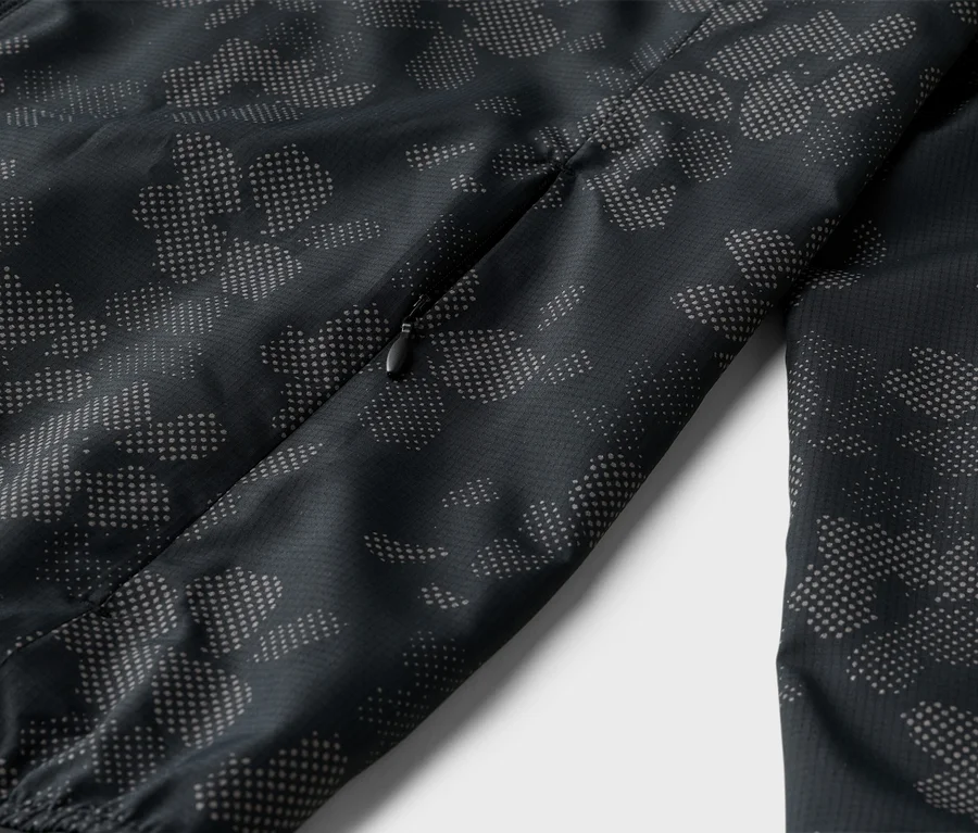 Nahaufnahme einer schwarzen Jacke mit Reißverschluss und einem Muster aus grauen Punkten.