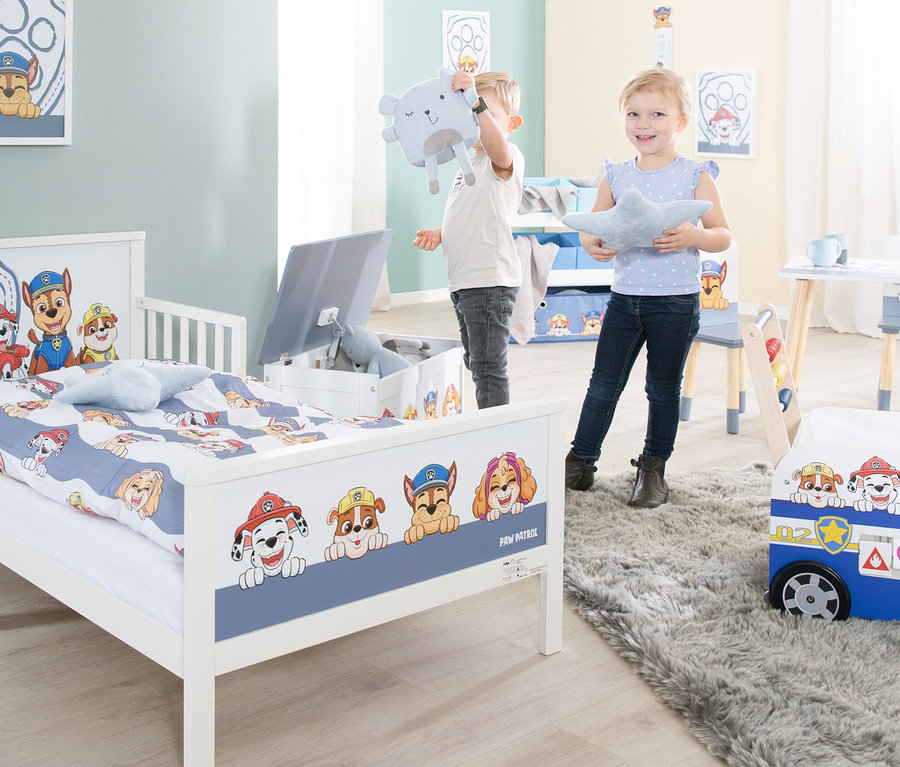 Zwei Kinder spielen in einem mit Paw Patrol Motiven dekorierten Kinderzimmer.