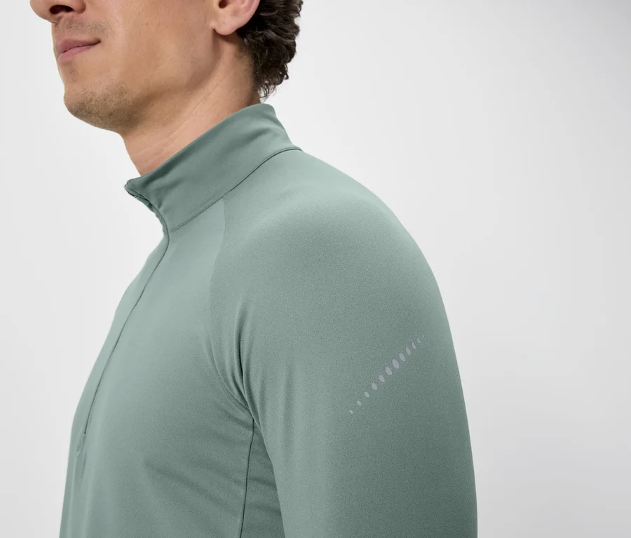 Nahaufnahme eines Mannes, der ein hellgrünes, langärmeliges Shirt mit Reißverschluss trägt.