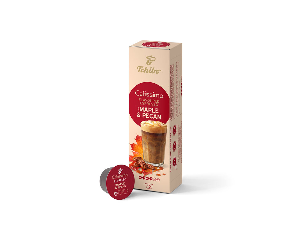 Eine beige Schachtel Cafissimo Flavoured Espresso Maple & Pecan (10 Kapseln) steht aufrecht, davor liegt eine einzelne dunkelrote Kapsel. Die Schachtel zeigt ein Kaffeegetränk, Ahornblätter und Pekannüsse.