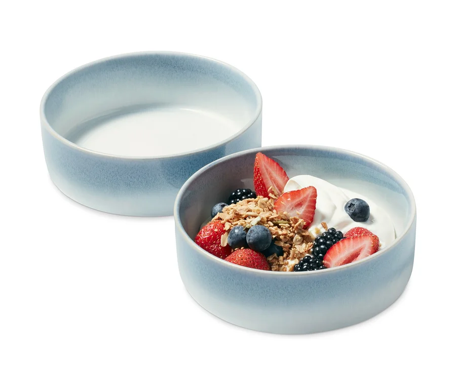 Zwei Schalen, eine leer und eine mit Joghurt, Müsli und Früchten.