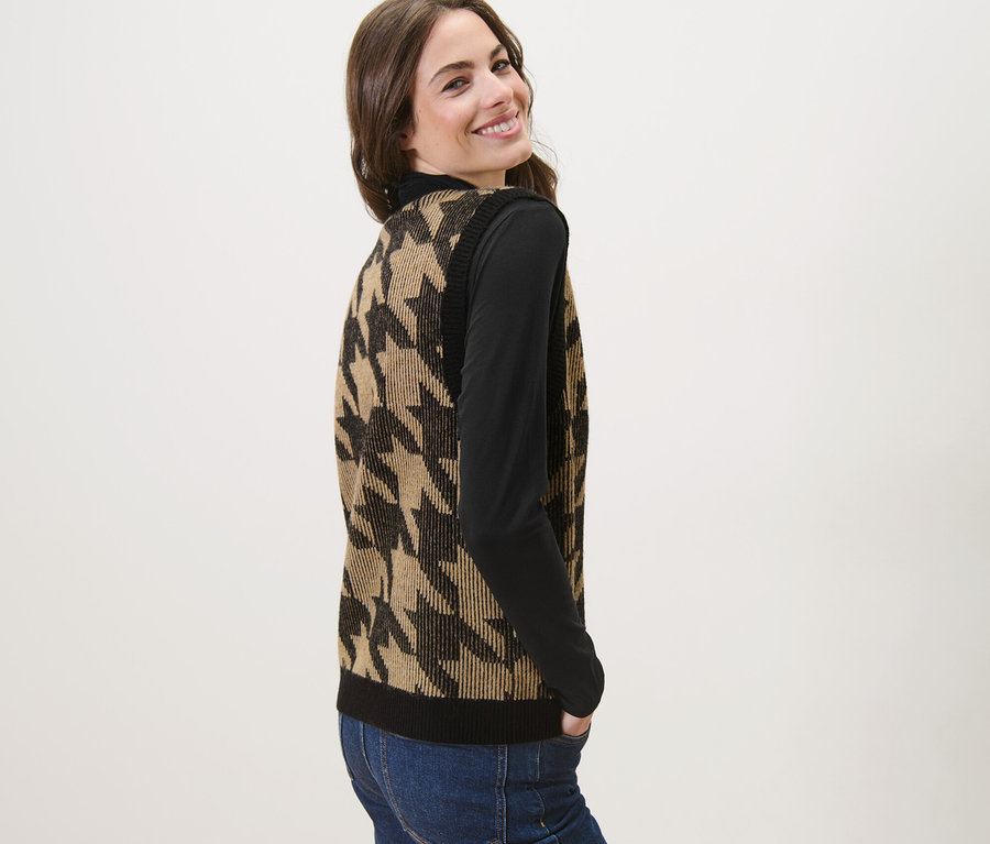 Frau lächelt über die Schulter und trägt eine Strickweste mit Hahnentritt-Jacquard.