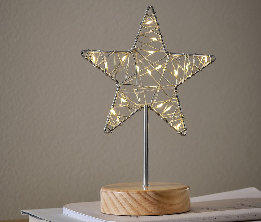 Eine LED-Dekofigur »Stern« steht auf Büchern auf einem Schrank.