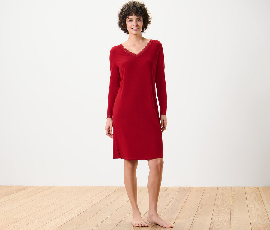 Frau steht barfuß und trägt ein rotes Nachthemd mit Spitzenbesatz.