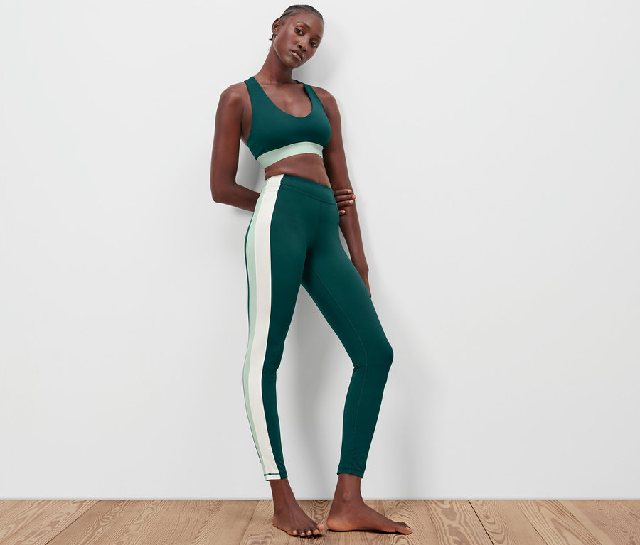 Frau posiert in Sport-BH und dunkelgrüner Sporttight.