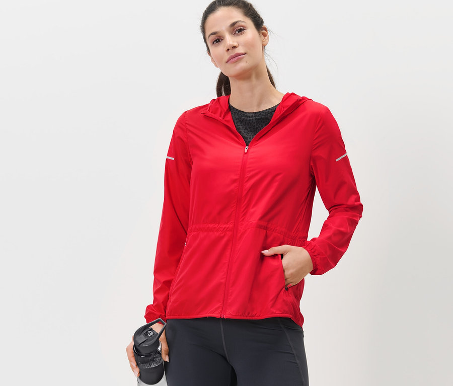Frau posiert in roter Lightweight-Laufjacke.