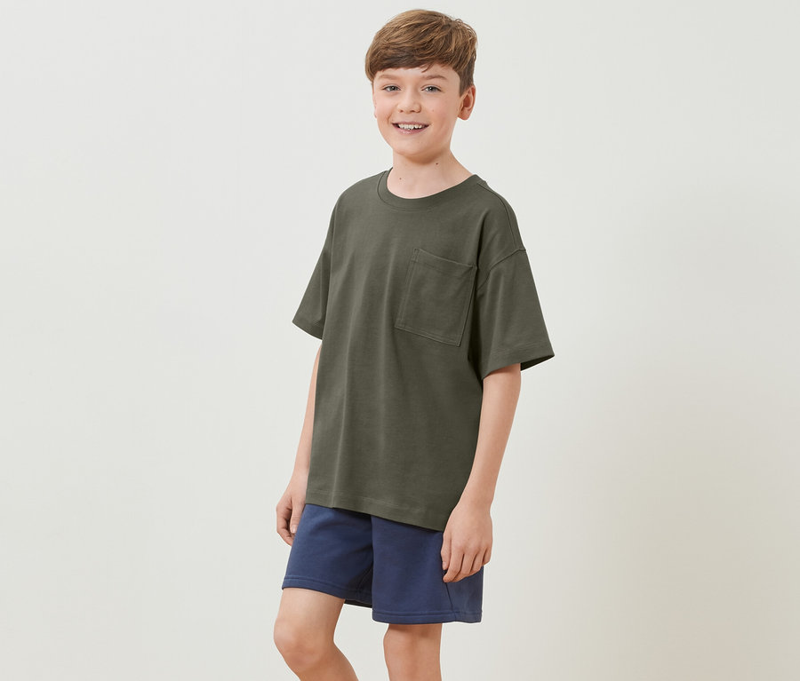 Junge trägt ein Kinder-Heavy-T-Shirt mit überschnittenen Schultern und blaue Shorts.