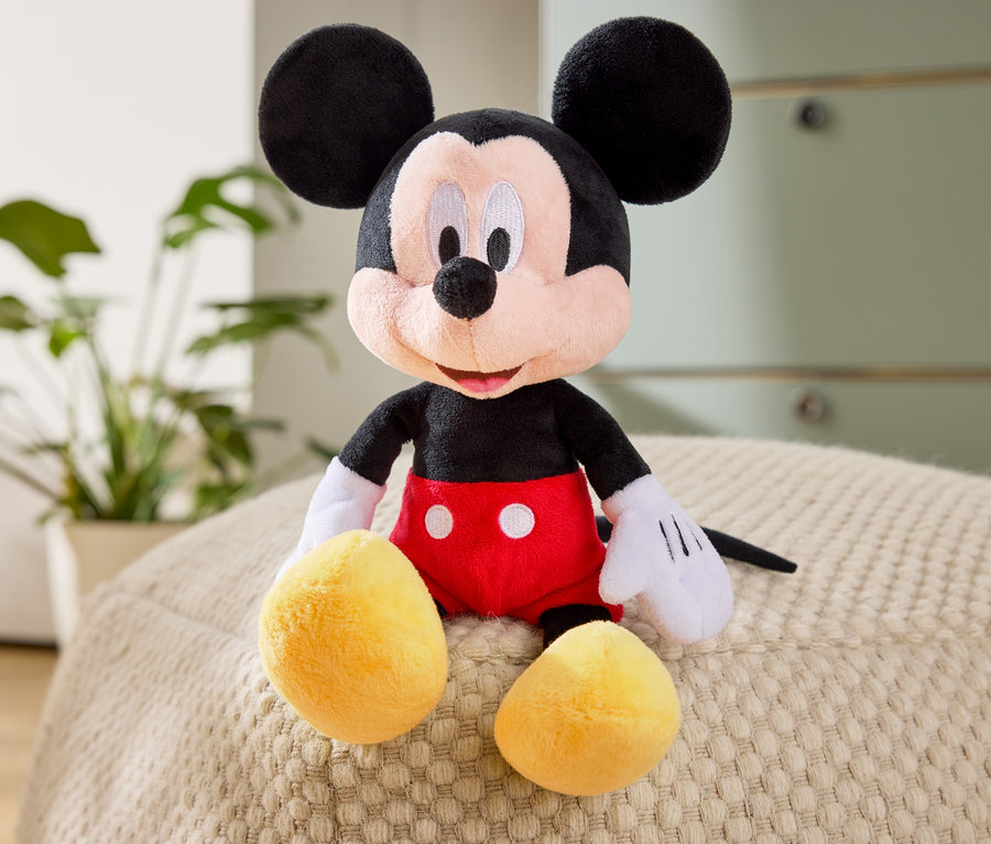 Mickey Mouse Stofftier sitzt auf einem Sitzkissen.