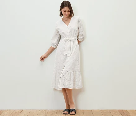 Frau steht und trägt ein Blusenkleid mit Lochstickerei.