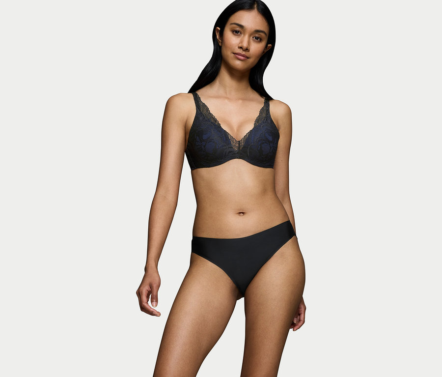 Eine Frau trägt einen schwarzen Spitzen-BH und schwarze Slips.