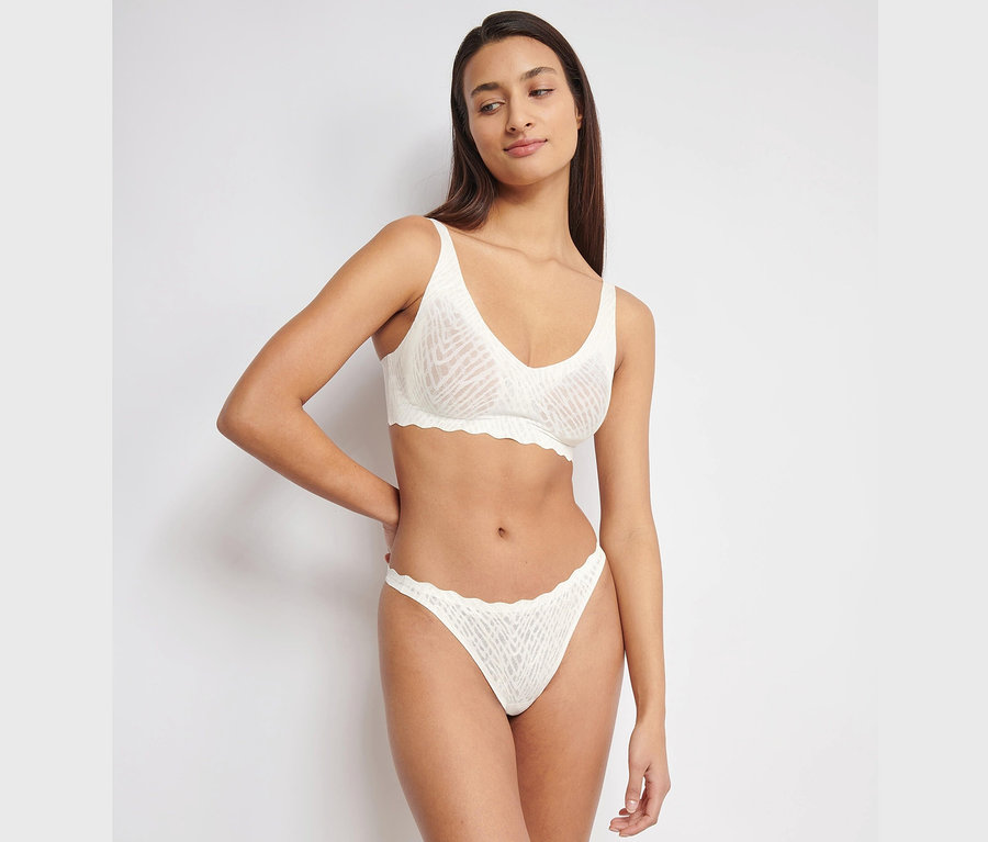 Frau posiert in weißer sloggi ZERO Feel Bliss Soft Bra Unterwäsche.