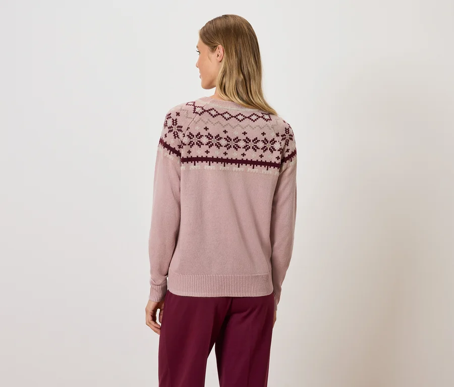 Frau von hinten in rosa Pullover mit geometrischem Muster und bordeauxfarbener Hose.