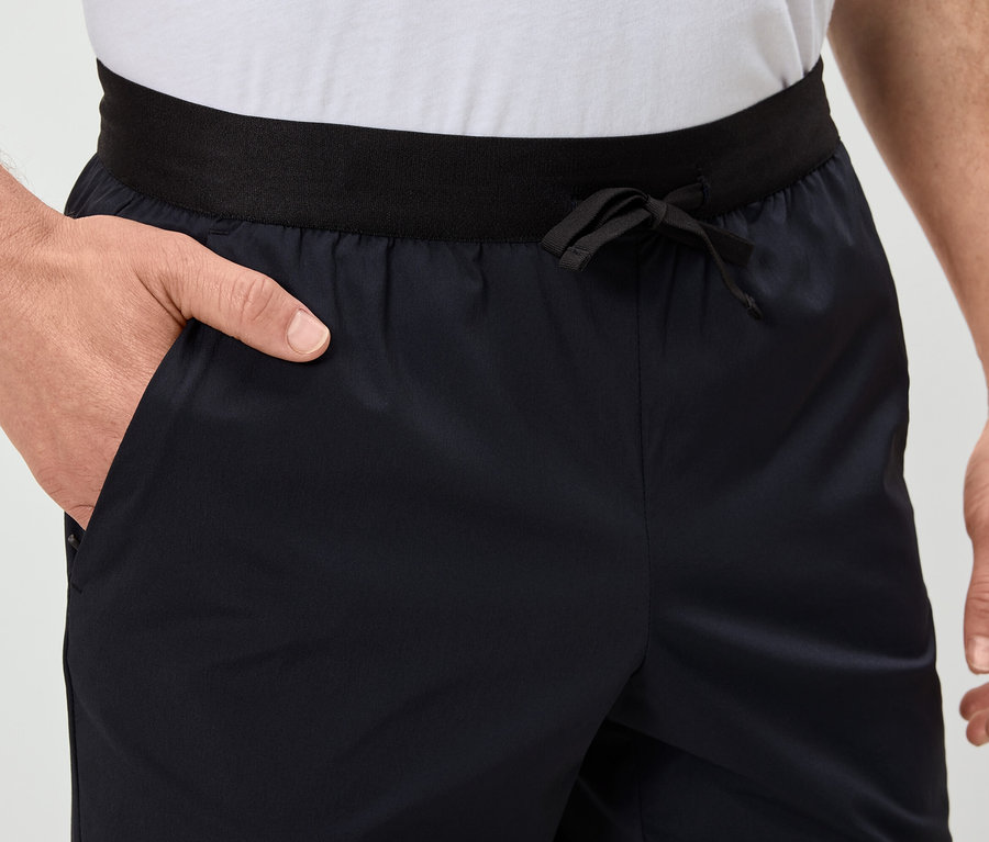 Mann hat die Hand in der Tasche von marineblauen Shorts mit schwarzem Bund.