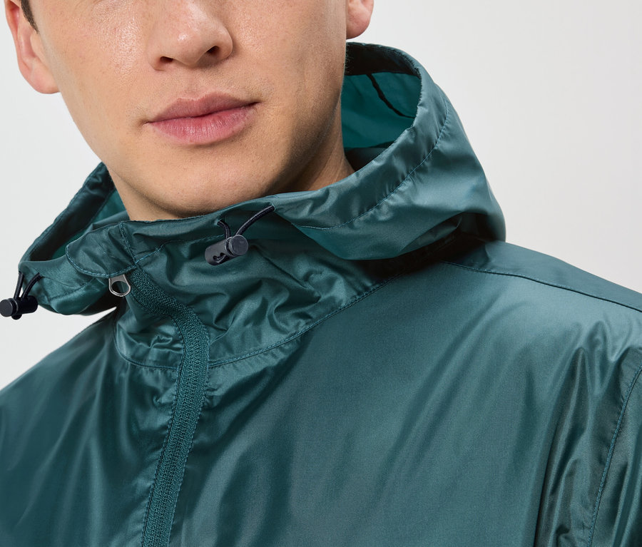 Nahaufnahme eines Mannes, der eine dunkelgrüne Regenjacke mit Kapuze trägt.