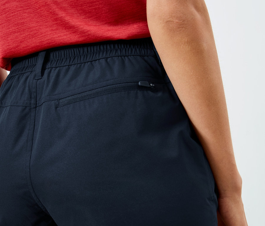 Nahaufnahme der Rückseite einer Person, die marineblaue Hosen mit elastischem Bund und Reißverschlusstasche trägt.