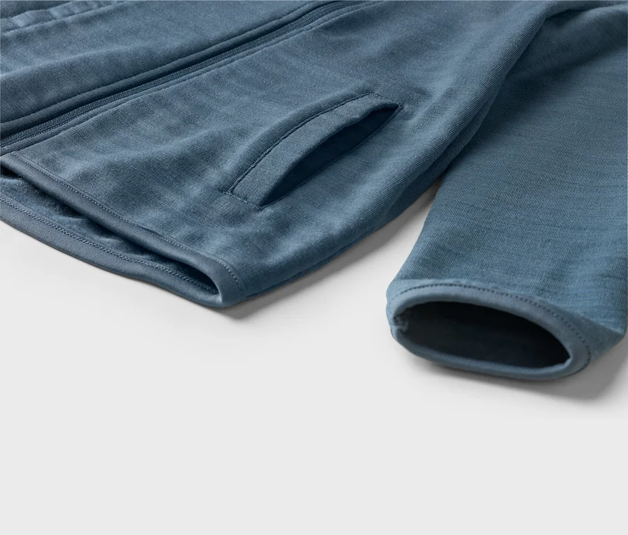 Nahaufnahme einer blauen Jacke mit Reißverschluss, einer Seitentasche und einem Ärmelbündchen.