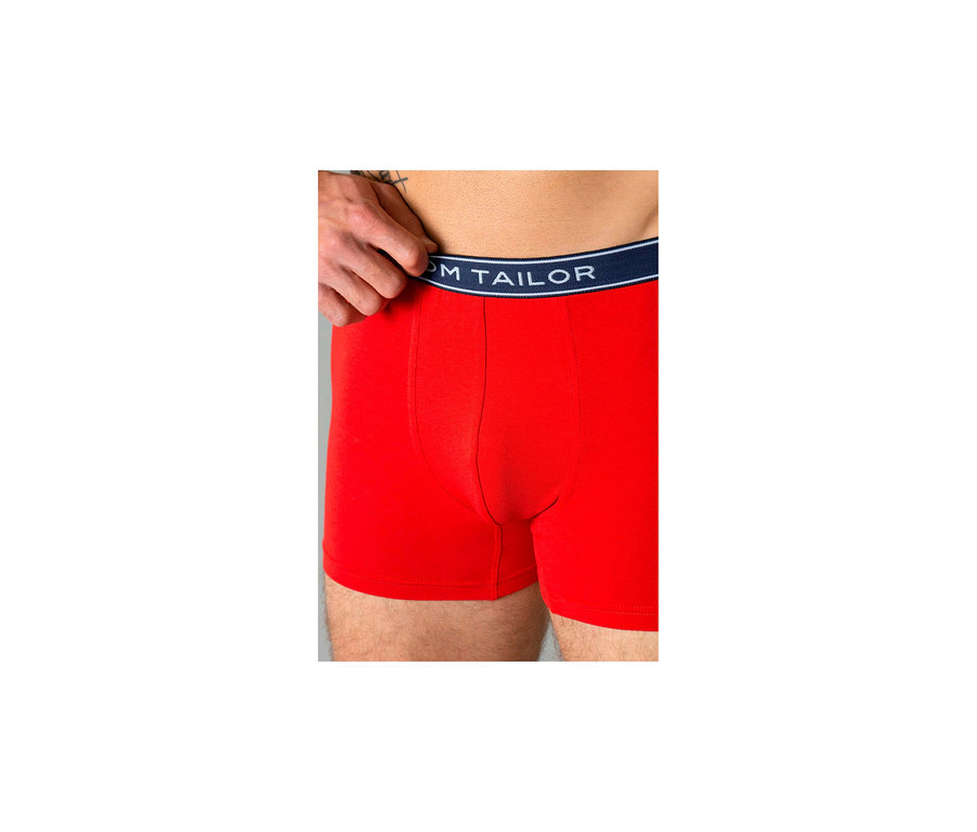 Mann trägt rote Tom Tailor „Buffer“ Slipboxer; eine Hand zieht den marineblauen Bund hoch.