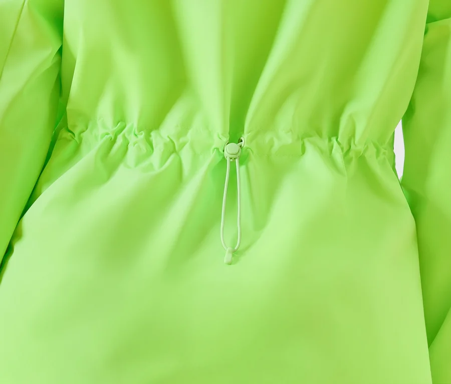 Detailansicht einer neongrünen Jacke mit Kordelzug in der Taille.