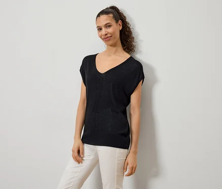 Frau trägt ein schwarzes V-Ausschnitt-Top und eine helle Hose.
