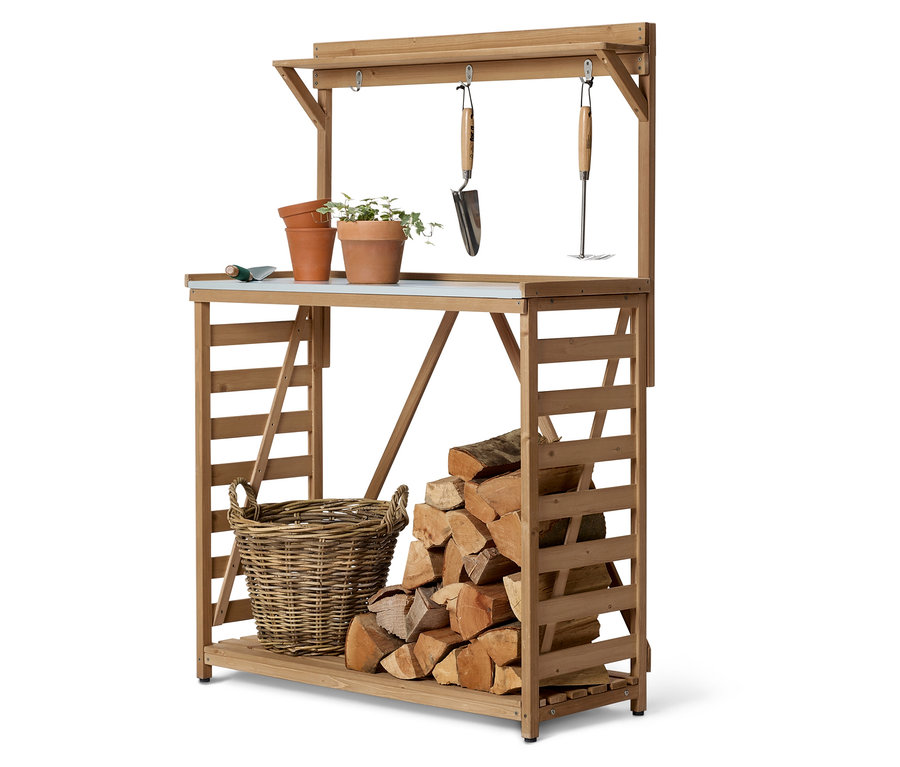 Ein hölzerner Gartentisch mit Pflanzen, Töpfen, Werkzeugen, einem Korb und Holzscheiten.
