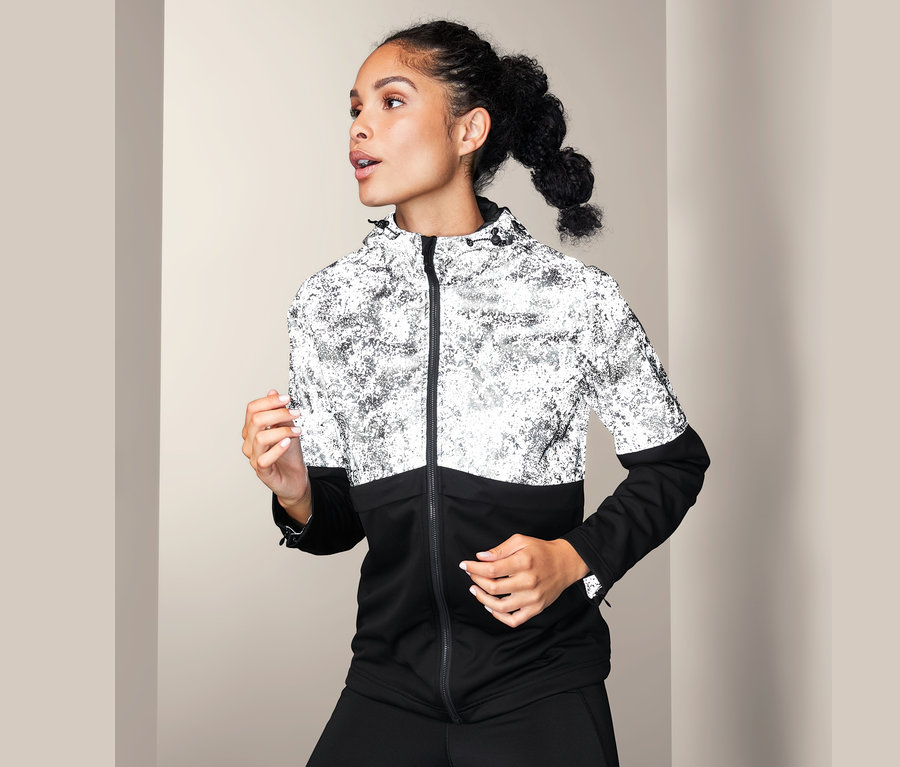 Frau trägt eine Softshelljacke mit dekorativen Reflektivelementen.