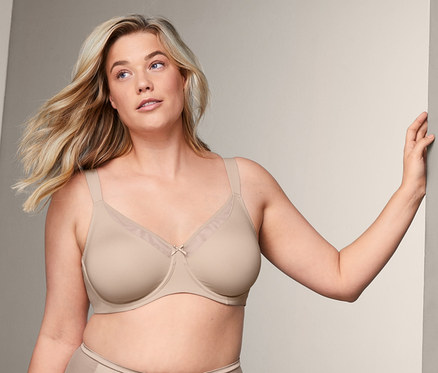 Blonde Frau posiert in beige Minimizer-BH und Höschen.