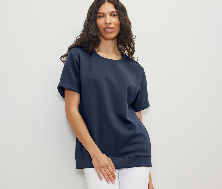 Frau trägt dunkelblaues Shirt aus Modalmix und weiße Jeans.