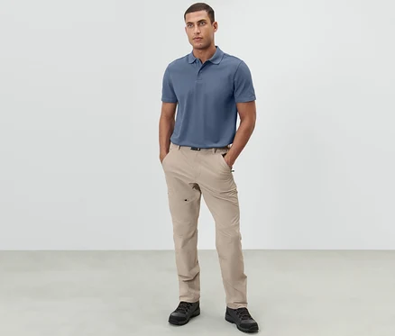 Mann steht mit den Händen in den Taschen einer hellbeigen Outdoorhose.