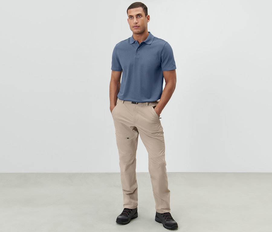 Mann steht mit den Händen in den Taschen einer hellbeigen Outdoorhose.