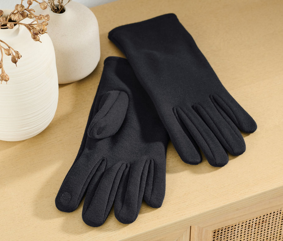 Auf einem Tisch liegen Sweathandschuhe neben zwei Vasen.