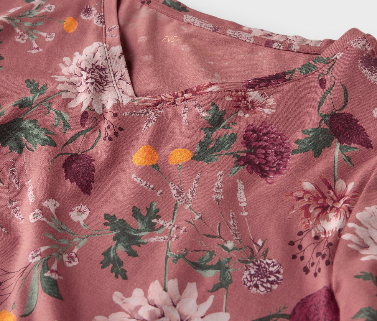 Detailansicht eines rosafarbenen Oberteils mit Blumenmuster.