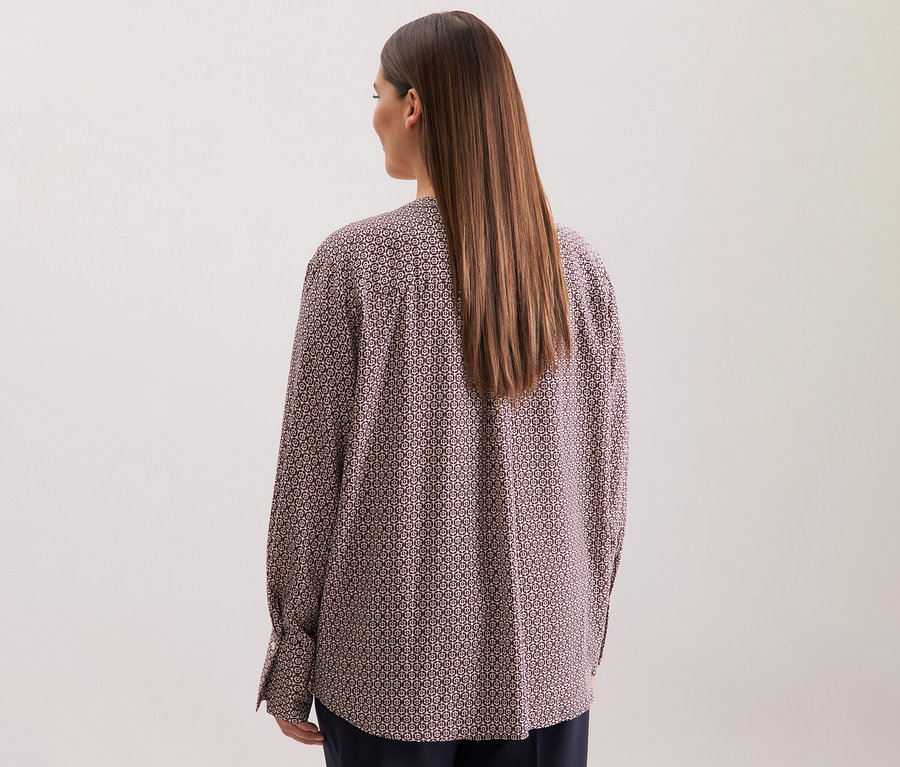 Rückansicht einer Frau mit langen braunen Haaren, die eine Seidensticker Tunika aus Viskose mit einem Alloverprint in Ecru und Burgunder trägt.