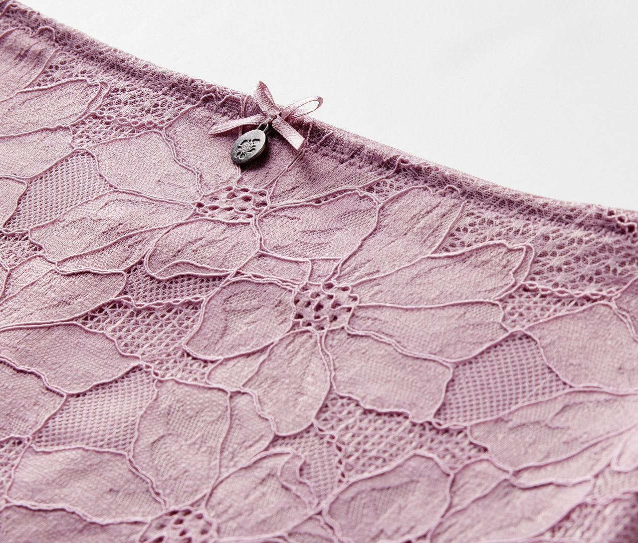Detail einer mauvefarbenen Highwaist-Panty »light-shaping« mit Blumenspitze und Schleife.