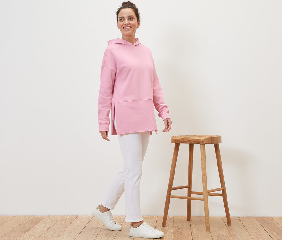 Frau geht und trägt ein langes Kapuzensweatshirt in Rosa.
