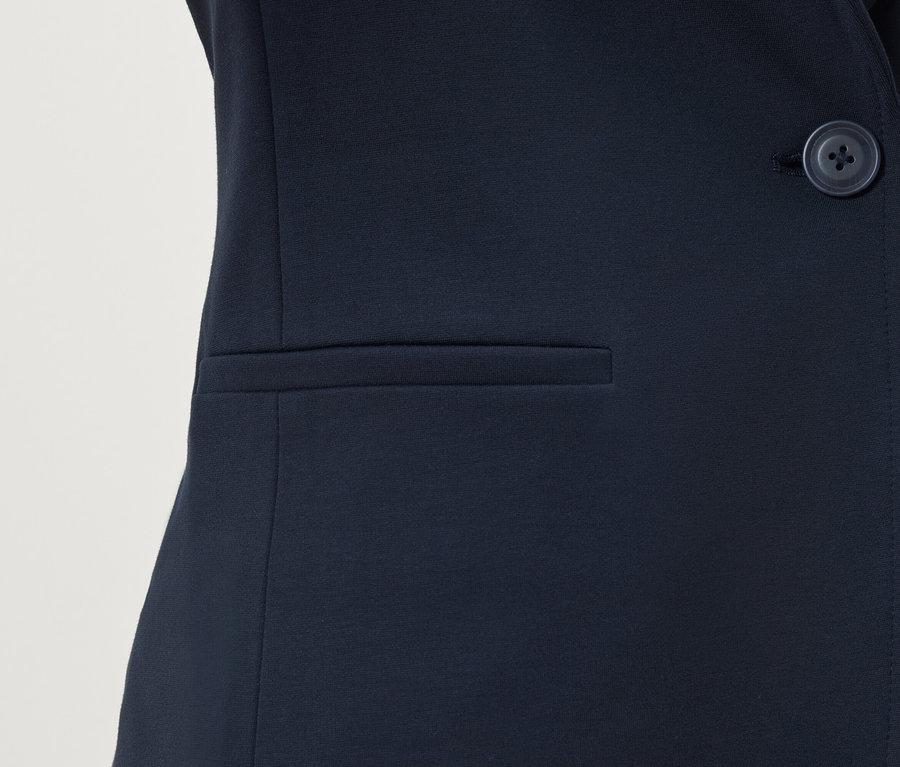 Detailaufnahme eines dunkelblauen Blazers mit Knopf und Tasche.