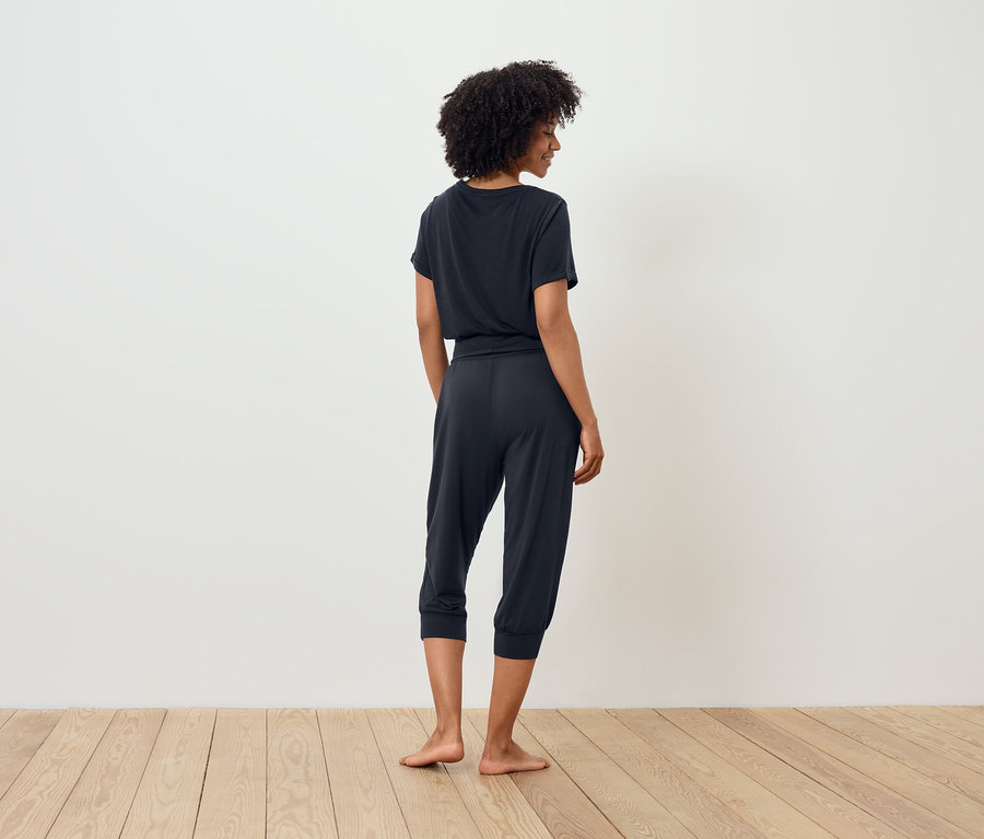 Frau in dunklem T-Shirt und Dreiviertelhose steht mit dem Rücken zur Kamera.