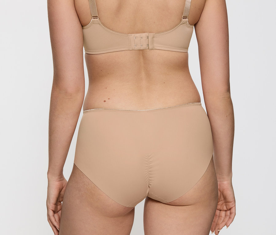 Rückansicht einer Frau, die einen hautfarbenen Triumph Essential »Minimizer W X«-BH und Slips trägt.