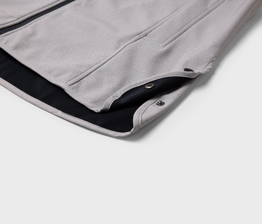 Detailaufnahme einer grauen Jacke mit schwarzem Futter und Druckknöpfen.