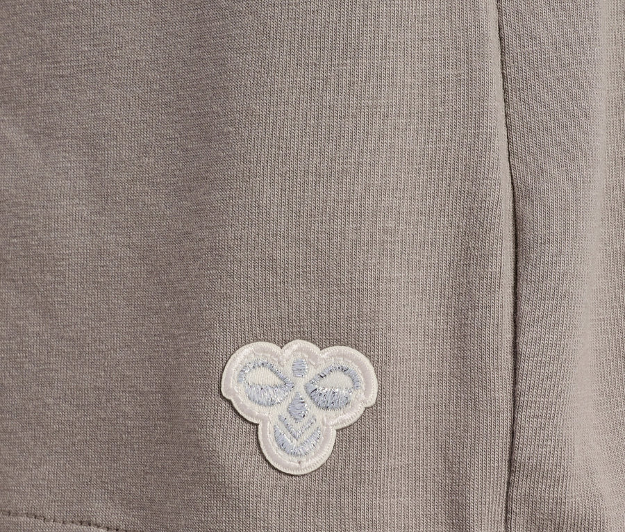 Detailaufnahme eines grauen Stoffes mit einem kleinen, aufgenähten, weißen Logo.