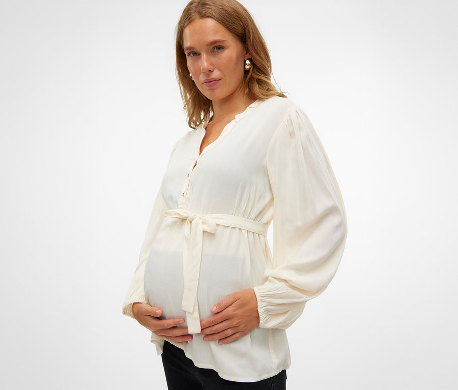 Schwangere hält ihren Bauch und trägt eine MAMALICIOUS MLMERCY LIA L/S WO TOP 2F NOOS.