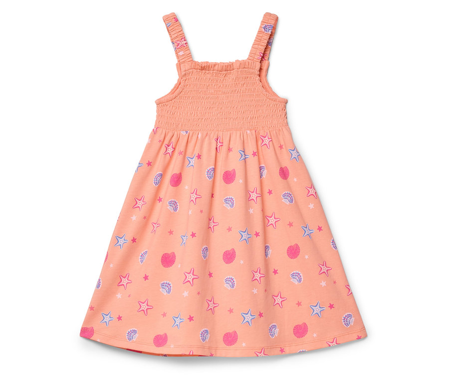 Ein pfirsichfarbenes Kleid mit einem Muster aus rosa Muscheln und blauen Seesternen liegt auf einem weißen Hintergrund.
