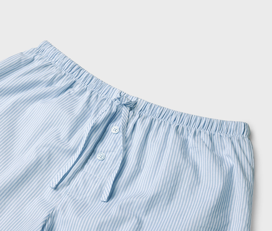 Detailansicht einer hellblau-weiß gestreiften Pyjamahose mit elastischem Bund und Knopfleiste.
