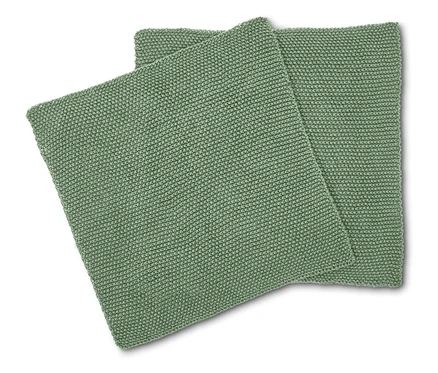 Zwei quadratische, hellgrüne Kissen mit Strickmuster liegen übereinander.