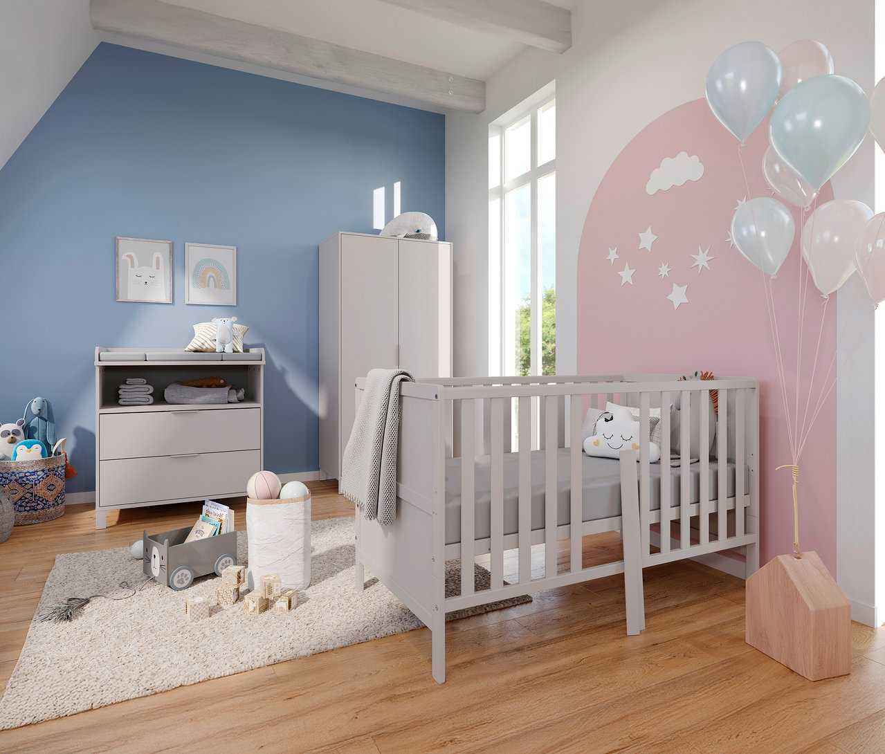 Ein Kinderzimmer mit einem grauen Kinderbett, einer Wickelkommode und einem Kleiderschrank vor einer blau und rosa gestrichenen Wand.